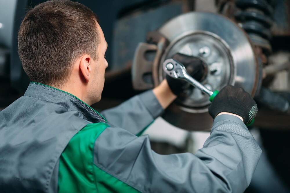 Mann i kjeledress bytter hjullager med verktøy